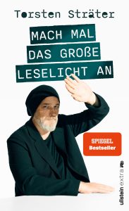 Cover von „Mach mal das große Leselicht an“: bärtiger Mann mit Beanie hebt Arm, weißer Hintergrund, Titel in grünen Balken.